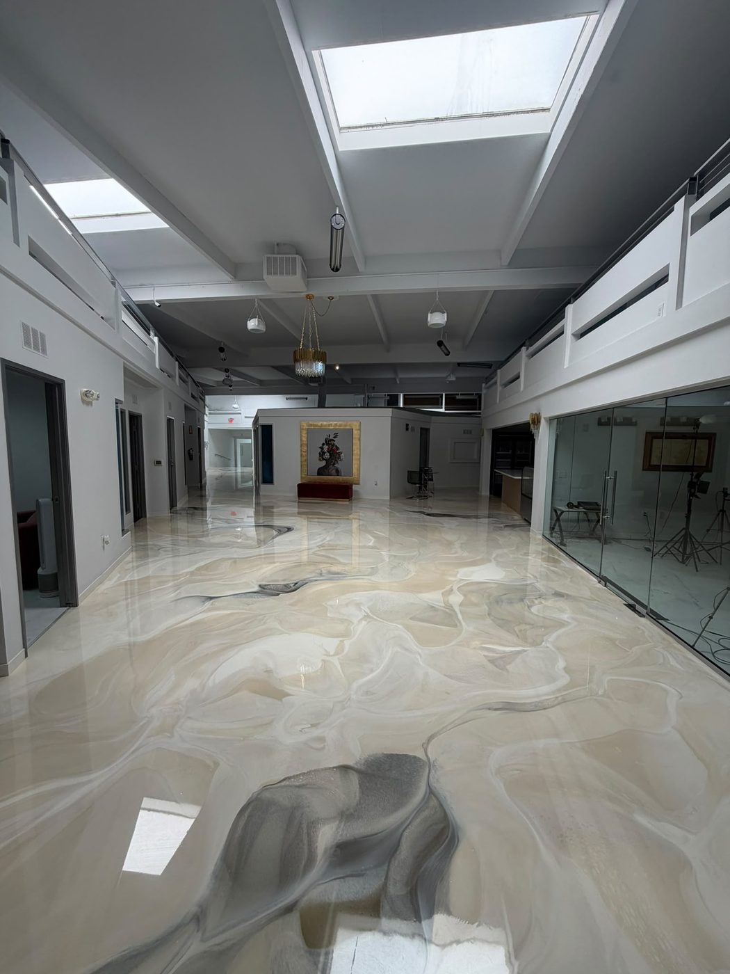 Sala principal con tragaluces, piso de mármol metálico y obra enmarcada en oro